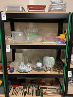 Shelving unit with assorted Tupperware containers on top shelves, glass vases and decorative items on middle shelf, cooking utensils on bottom shelf.