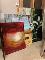 Three original signed paintings on canvas leaning against the wall showing all three artworks in one frame.