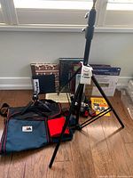 Photo showing vintage Pentax camera case, large tripod, small tripod, Cameron bag, scrapbooks and notebooks