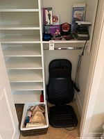 Closet shelf and floor area showing Renpho massage chair on floor along with basket containing smaller items and white shelving unit.