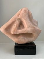Front angle view of abstract pink alabaster sculpture on black base.