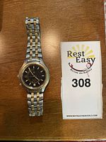 Front view of the Seiko Kinetic watch showing the black dial and two-tone metal bracelet laid flat on a wooden surface.