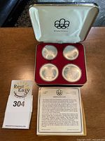 Open presentation case showing all four coins and informational insert