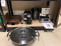 Shelf view showing all items: hot plate griddle, Nespresso frother, blender jar, blender base and Breville espresso machine with instruction sheet, plus wok on floor.