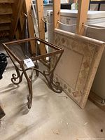 Photo showing separate stone tabletop leaning against rusty steel base with curled legs.