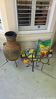 Photo showing the terracotta chiminea, Miracle-Gro sealed potting soil, Miracle-Gro plant food, metal stands, gardening brush, tool set, and spray bottle.
