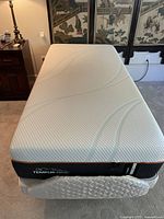 Front-left perspective of white memory foam mattress on quilted foundation and wooden base.