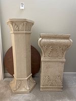 Front view of the two decorative stone display pillars side by side with round wooden slab visible behind them.