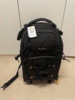 Front view of the Vanguard Alta Fly 58T camera travel bag with tags attached, showing its multiple compartments and built-in wheels.