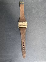 Full view of vintage Sicura watch showing rectangular gold-tone case and brown leather strap.