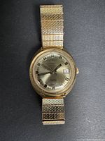 Full view of the men's vintage Timex wristwatch with gold-tone metal band and round dial.