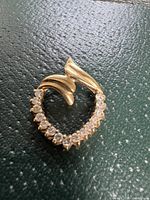 Front view of heart-shaped pendant showing diamonds along bottom curve and smooth gold abstract design at top