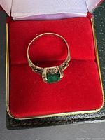 Front view of ring showing emerald-cut green stone and four-prong setting
