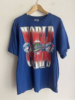 Blue vintage 1992 Toronto Blue Jays World Champs T-shirt hanging on wooden hanger showing front print.