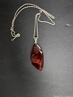 Full view of the vintage 925 sterling silver amber pendant necklace with twisted rope chain on dark background.