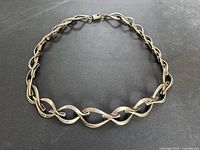 Full view of twisted link vintage 925 sterling silver necklace against a dark surface.