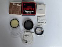 Vintage Asahi Pentax polarizing camera lens filters and accessories laid out including original boxes, filters in cases, and adapter ring.