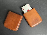 Two brown leather card holder cases shown side by side on a dark surface, each with an Ace of Hearts card partially visible.