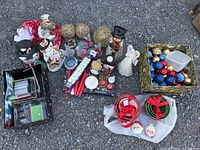 Photo showing assortment of holiday candle holders including snowman, Santa, and angel designs; gold and colorful balls; nesting mixing bowls tied with ribbons; Santa and Mrs. Claus salt and pepper shakers; and decorative items.