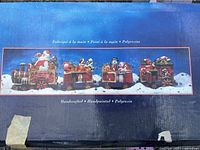 Box image showing label indicating handcrafted, handpainted, polyresin material for Christmas train set.