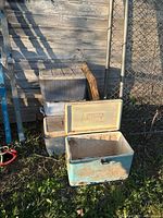 Four vintage Coleman coolers stacked and arranged outdoors, showing wear and condition differences