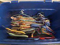 Blue bin holding assorted hangers including tied metal, colorful plastic, and some wooden ones.