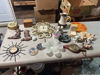 Wide view of table with assorted knick knacks including ceramic animals, clock, scale, dishes and carafes