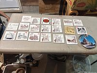 Overview of 19 local historical landmark ceramic trivets arranged on a table