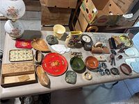 Full table overview showing various decorative trays, bowls, small collectibles, and the floral oil lamp on the left side.