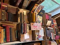 Multiple boxes filled with assorted old books of various sizes and conditions shown from above in a garage setting.