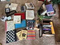 Multiple photo albums and photo sleeves arranged on carpet floor showing variety of prints and styles