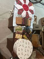 Overall lot arrangement showing three groups of folded fabric ends on a white quilted surface along with the round fabric box