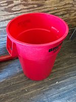 Single red Rubbermaid Brute trash can showing side and top view, highlights round shape and handles