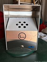 Front view of rectangular stainless steel smokers receptacle with a lock and cigarette symbol on the front panel.