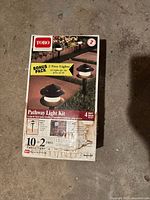 Front of box showing Toro Pathway Light Kit branding, 12 lights including 2 free bonus lights, 4 watt bulbs, new in box.