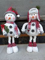 Two standing snowmen in red and white winter accessories, showing front views.