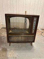 Front view of the vintage TV cabinet shell showing the glass screen, control panel, and speaker grille.