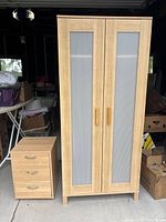 Wooden wardrobe and side table with three drawers shown side by side