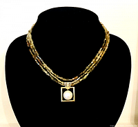 Full necklace on bust showing pendant and three gemstone strands