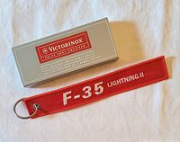 Victorinox branded box beside red F-35 Lightning II key fob