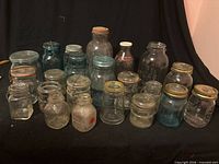 Front view of 22 assorted vintage jars and bottles showing colours, embossing and lids