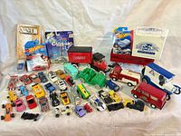 Full assortment of vehicles laid out including packaged Hot Wheels, boxed model, loose cars and larger trucks