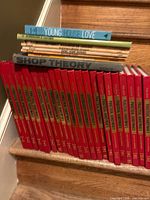 Row of red encyclopedia volumes with additional hardcovers on stair step