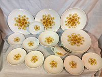 All pieces arranged showing floral pattern; includes dinner plates, salad plates, bowl, lidded sugar bowl