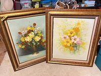 Both framed floral oil paintings side by side
