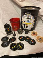 Group shot of all items including tin, buckets, match holder, bell, resin coal scuttle, chalkware plaque and eight coasters