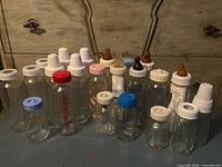Group view of all 22 glass baby bottles with assorted caps and nipples