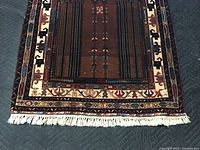 Close up of wool prayer rug fringe edge, showing detailed geometric patterns and colors.