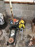 Green floor jack with handle, bottle jack next to it, and yellow portable jump starter on concrete floor