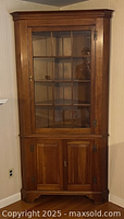 Full front view of the corner cabinet with glass upper door and lower wood doors closed.